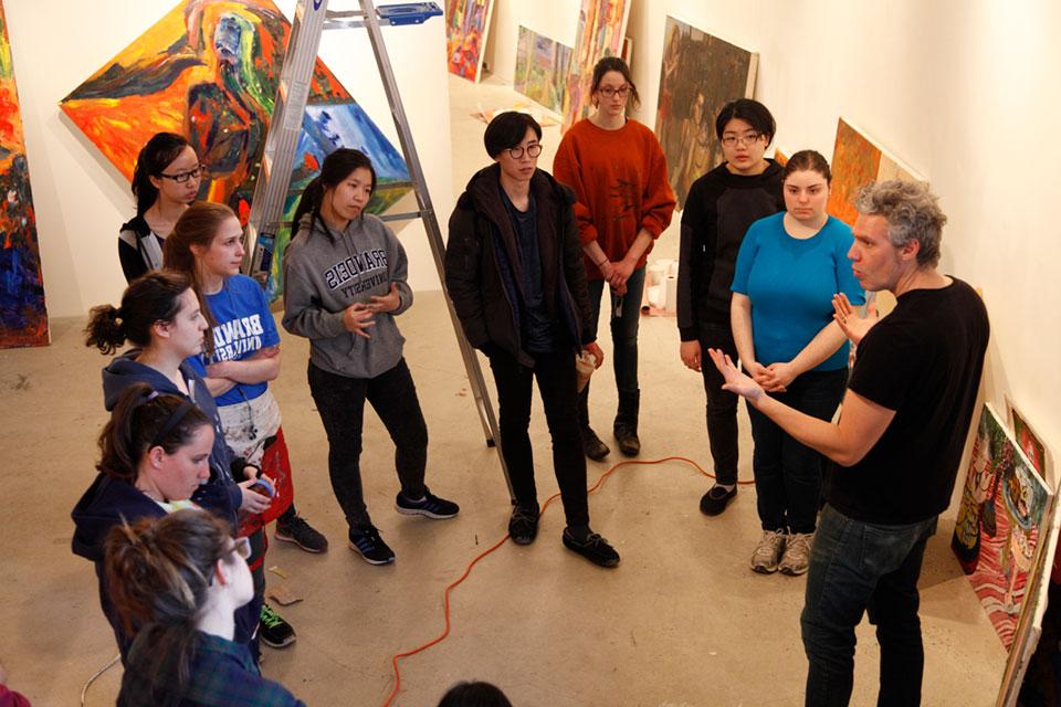 A professor talks with students in an art gallery
