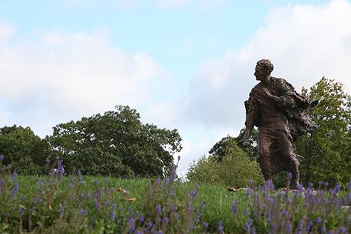 路易斯·365betapp的雕像站在紫色的花丛中