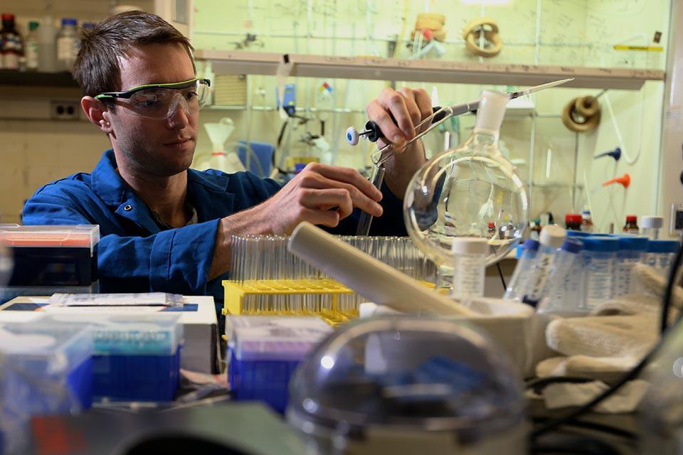 male student conducting a science experiment in lab with test tubes
